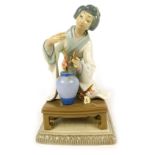 A Lladro porcelain figure of a geisha seated before vase of blossom, on a rectangular base, 20cm hig