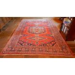 A large Middle Eastern carpet, red and blue ground with central medallion, within borders, 348cm x 2