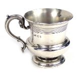 A George IV silver christening mug, of baluster form, with incised banding, scroll handle, on a step