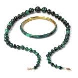 Malachite jewellery, comprising a malachite and brass bangle, 8cm diameter, and a graduated single s