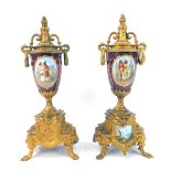 A pair of Continental gilt metal and porcelain clock garnitures, of urn form, each decorated central