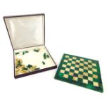 A malachite chess board, 19cm x 19cm, together with carved malachite and soapstone pieces. (AF)