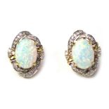 A pair of clip earrings, centred by an imitation opal surrounded by tiny diamonds, in a yellow gold