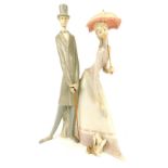 A Lladro figure group of lady and gentleman, walking with dog, lady with parasol, gentleman with loo