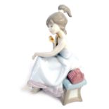 A Lladro porcelain figure of a young girl, seated on a bench beside telephone, with dog to base, 22c