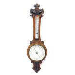 An early 20thC carved oak cased barometer, with cream enamel dial, and mercury Fahrenheit and Centig