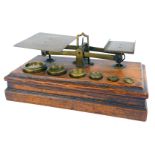 A set of early 20thC brass postage scales, on a stepped oak base, together with six weights ranging