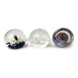 Three glass paperweights, comprising a Caithness purple bubble paperweight, a Caithness ER 1977 comm
