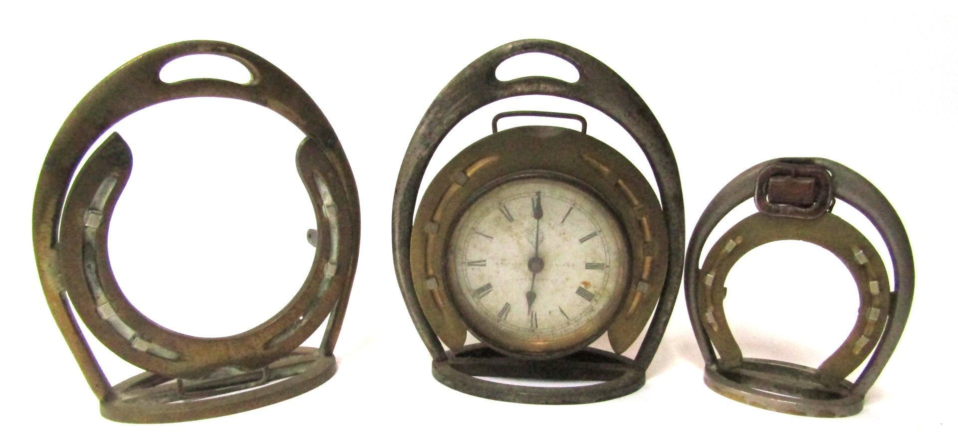 Three novelty clock stands, formed from a stirrup with horseshoe mount, one including clock face sta