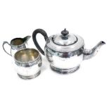 An Elkington & Co silver three piece tea set, in the arts and crafts style, with ebonised handle and