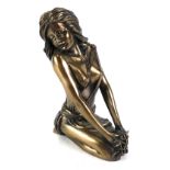 A resin and bronze effect semi-nude female, seated, 21.5cm high.