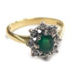 An 18ct gold emerald and diamond cluster ring, the oval emerald in claw setting with snowflake type