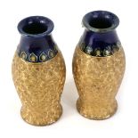 A pair of Royal Doulton stoneware vases, each with incised decoration in gilt, below a band of styli