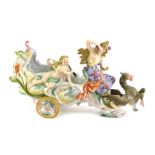 A German porcelain centrepiece, modelled in the form of female figure and a putti, on a chariot pull
