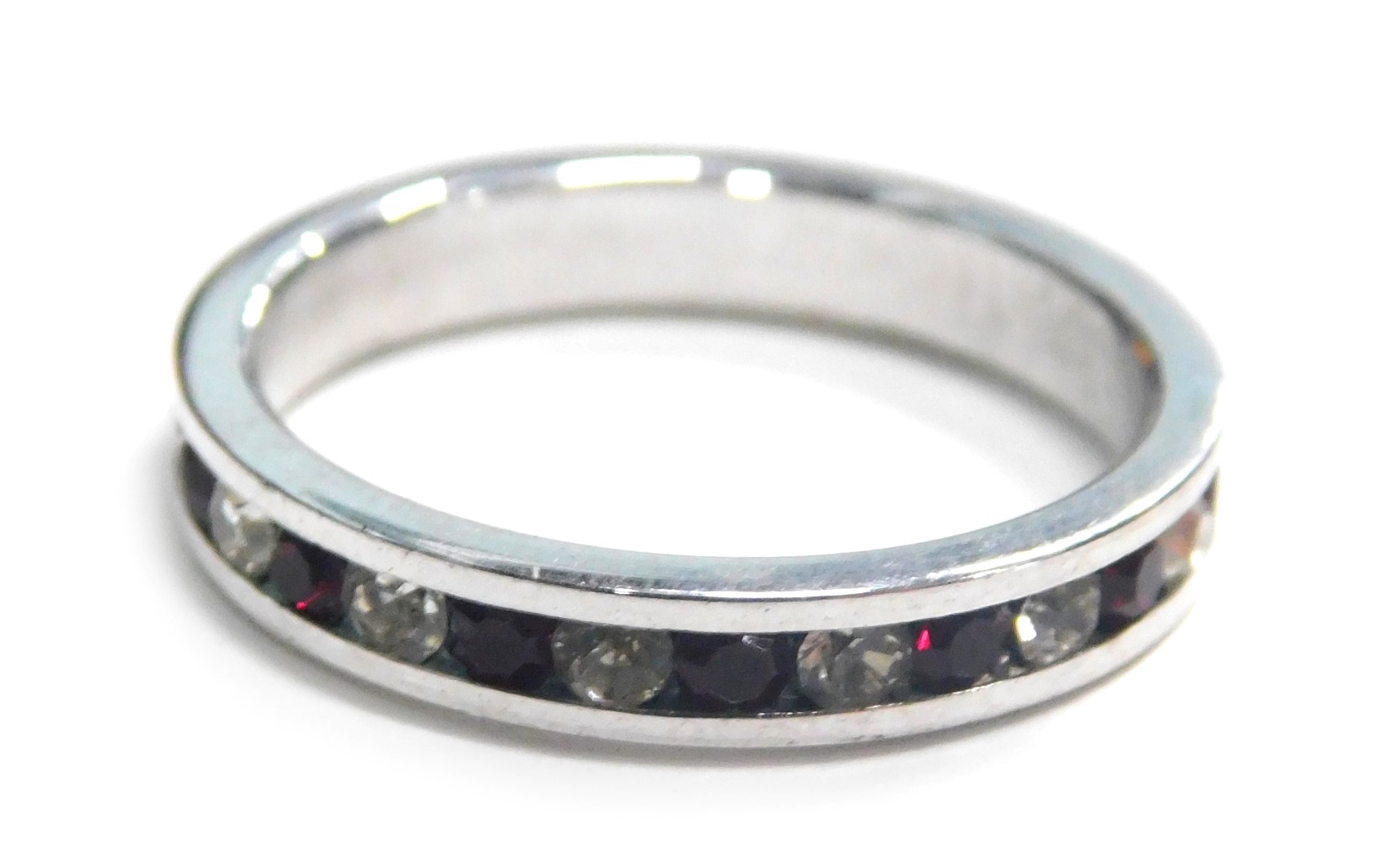 An eternity ring, tension set with red and white paste stones, in a silver coloured band, unmarked,