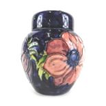 A Moorcroft pansy pattern jar and cover, on a blue ground with pink and purple flowers, 12cm high.