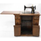 An unusual Singer treadle freestanding cased sewing machine, in a heavily carved cabinet with cup h