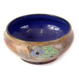 A Royal Doulton stoneware shallow bowl, with tube lined decoration of flowers and leaves, impressed