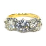 An 18ct gold three stone ring, set with two diamonds and one paste stone, the outer diamonds approx