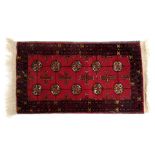 An Afghan Bakhara red ground prayer rug, decorated with ten central medallions, and cross motiffs, w