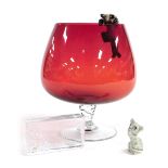 A late 20thC novelty ruby glass oversized brandy balloon, set within a pottery mouse, with a cat on