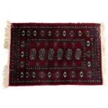 A Baluch red ground prayer rug, decorated with six central medallions, within repeating floral and g