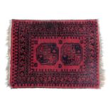 An Afghan Nahzat red ground prayer rug, with two central medallions within repeating foliate and flo