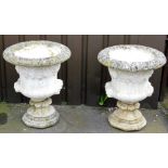 A pair of reconstituted garden urns, of fluted baluster form, with twin mask head handles, beneath a