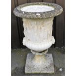 A reconstituted garden urn, of partially fluted form, with twin mask handles, beneath a band of clas