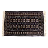A Bokhara blue ground rug, decorated with two rows of eleven medallions, interspersed with floral mo
