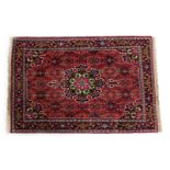 A Persian Shiraz red ground rug, decorated with a central floral medallion, in a floral ground, with