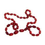 A string of graduated cherry amber beads, with forty-four beads, the largest 2.5cm wide.