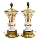A pair of late 19thC milk flashed glass vases, converted to table lamps, painted with flowers, the