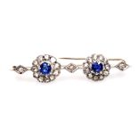 An Edwardian sapphire and diamond bar brooch, set with two rose cut sapphires, in a circular surroun