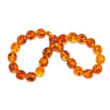 A string of amber cylindrical beads, comprising twenty-five beads on an amber screw clasp, each bead