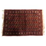 A Bakhara red ground rug, decorated with four rows of fourteen medallions, within repeating floral a