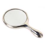 A hand held silver mounted dressing table mirror, with circular top, in a white metal case, hallmark