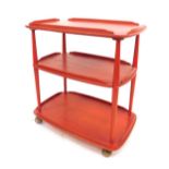 A painted Ercol three tier trolley, in red, on castors, 75cm high, 67cm wide, 46cm deep.