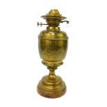 An early 20thC duplex brass oil lamp, with engraved decoration, raised on a wooden base, no chimney