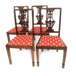 A set of four 20thC oak dining chairs, each with a pierced carved splat, drop in seat, on front turn