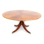 A reproduction flame mahogany inlaid dining table, the circular top raised on a turned column, on sa