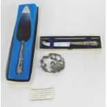A silver handled shell pattern cake slice, a silver handled cheese knife, and a plated swan arch