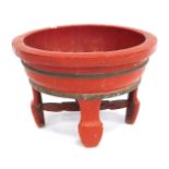 A Chinese red painted planter, with metal banding, 34cm high, 54cm wide. (AF)