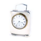 A George V silver cased travelling clock, fitted with a white enamel dial, blue hands, brass outer b