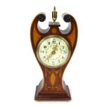An Edwardian mantel clock, of scroll form, with brass bulbous central finial, with a cream enamel nu