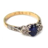 An 18ct gold sapphire and diamond dress ring, the central oval sapphire in claw setting, flanked by