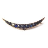A 9ct gold sapphire crescent moon brooch, set with graduated design sapphires, with pierced outer bo