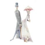 A Lladro figure group of lady and gentleman, walking with dog, lady with parasol, gentleman with loo