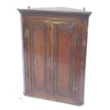 A 19thC oak hanging corner cabinet, the top with a moulded edge above two panelled doors, 98cm high,