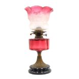 A Victorian cranberry glass oil lamp, the flared shade with etched floral detail and a cranberry gla